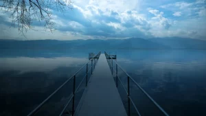 Fokus schützen, besser fuehren Bild vom Steg, glasklarer See, Berge in der Ferne, blaues Licht